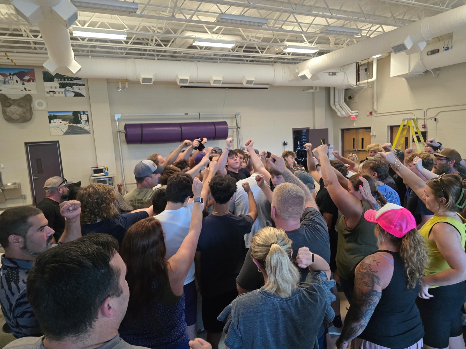 Mascoma Football players, coaches, and families joining hands at the season opening gathering
