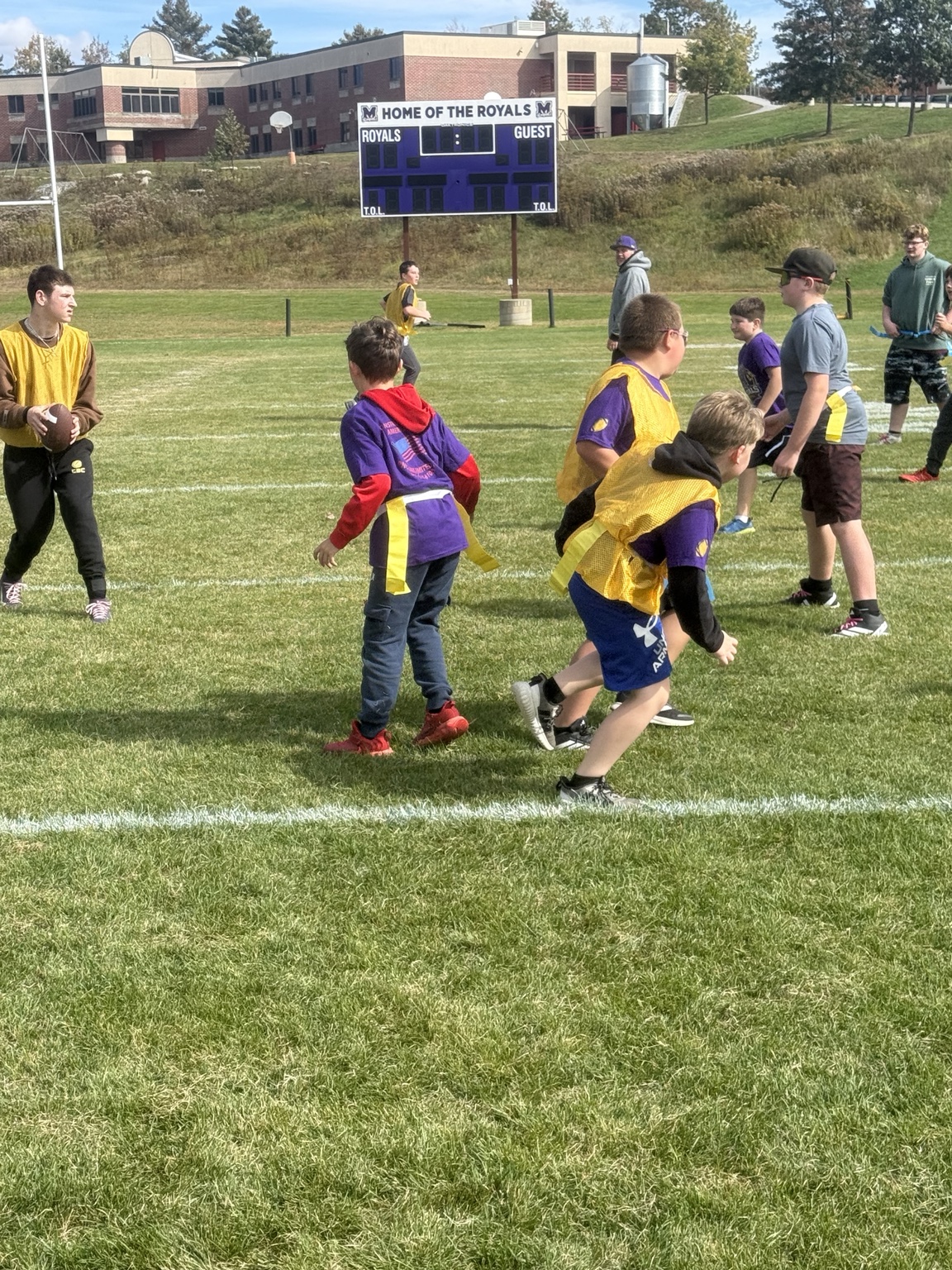 Jr Royals playing youth flag football on Mascoma's varsity field beneath the Home of the Royals scoreboard
