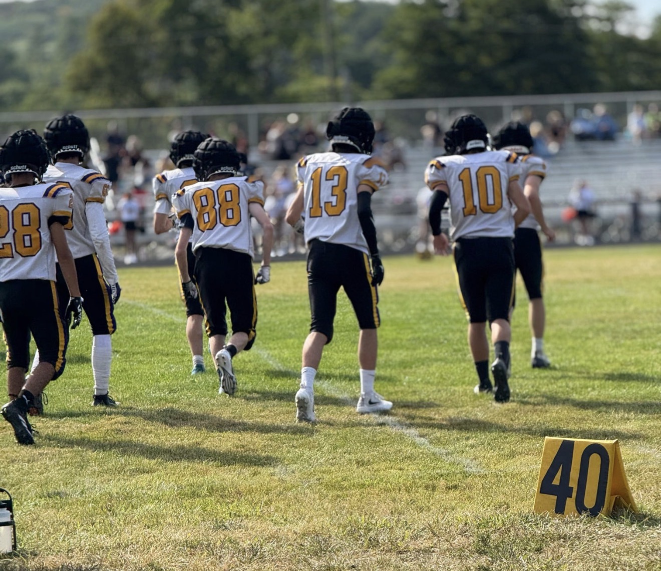 Mascoma Royals players in white jerseys heading onto the football field together